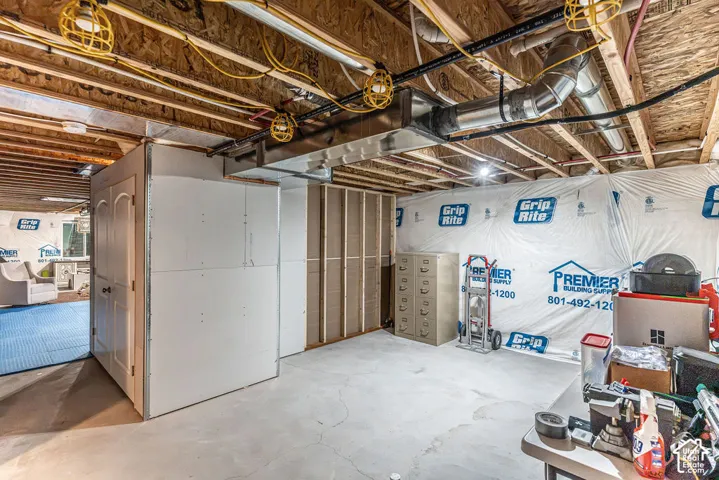 Unfinished basement area with visible ceiling joists, exposed ductwork, and concrete flooring