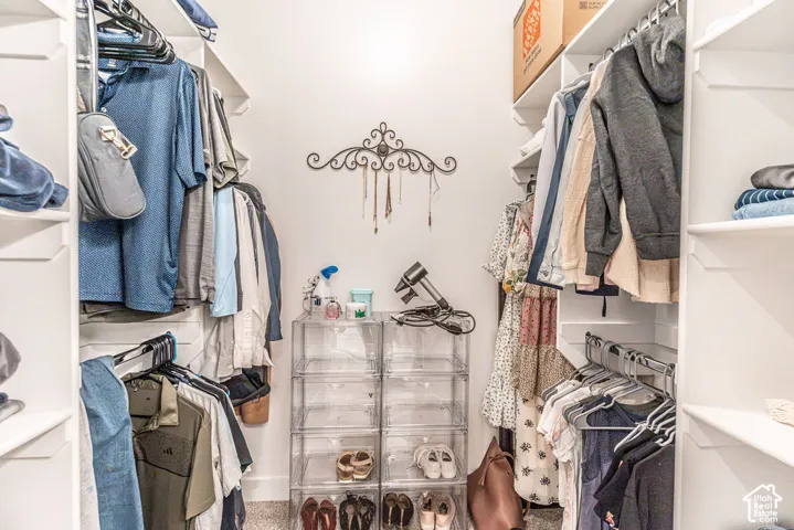 Walk-in closet featuring white built-in shelving, multiple hanging rods, and a neutral wall color