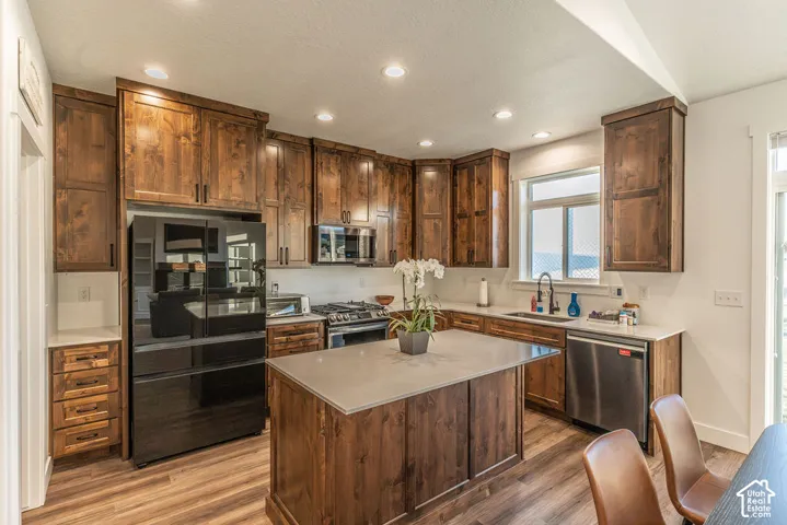 Kitchen featuring wood-finish flooring, recessed lighting, wood cabinetry, stone countertops, and a center island