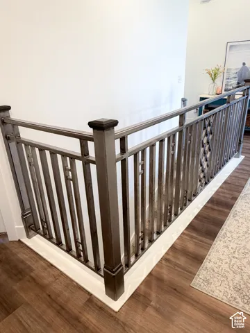 Wrought iron railing with decorative balusters and square newel posts, paired with wood-finish flooring and white trim