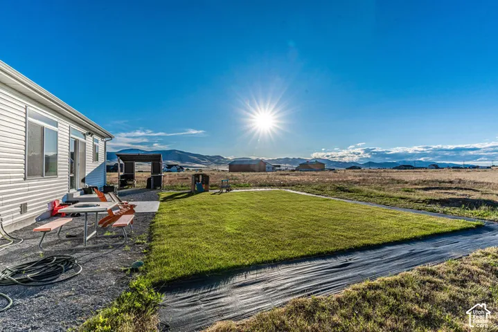 Expansive backyard featuring a manicured lawn, gravel patio, and mountain backdrop