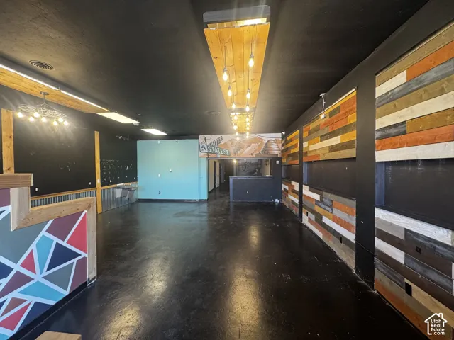Spacious commercial interior featuring dark flooring, varied wood-finish paneling, and a unique geometric pattern wall accent