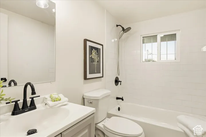 Vanity with a white countertop and matte black fixtures, full bathtub, and white subway tile surround