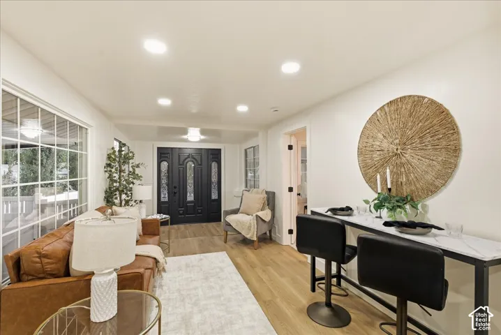 Recessed lighting throughout, wood-finish flooring, a decorative entry door with sidelights, a built-in console table with a stone-look surface, and large picture windows