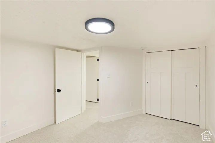 Neutral-toned carpet, white walls, and a contemporary flush-mount ceiling light