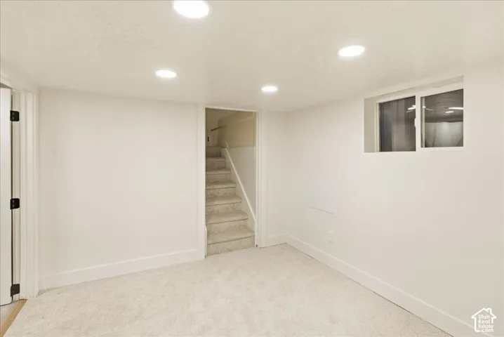 Recessed ceiling lighting, white walls, light-colored carpeting, white trim, and a window