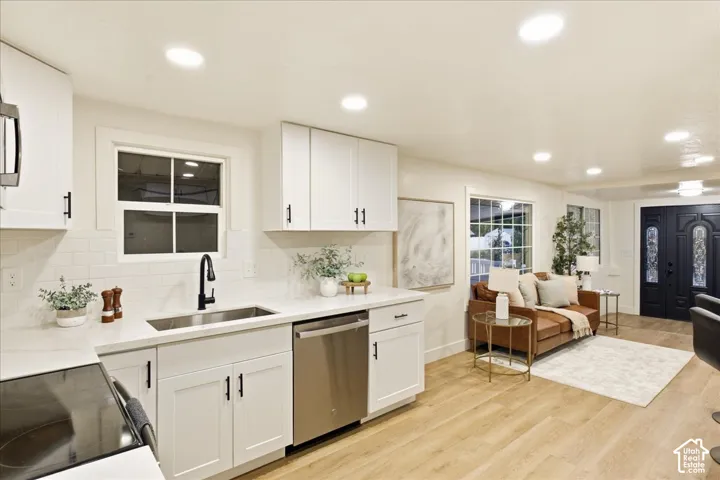 Recessed lighting, wood-finish flooring, white shaker cabinetry, stainless steel appliances, and a dark double entry door