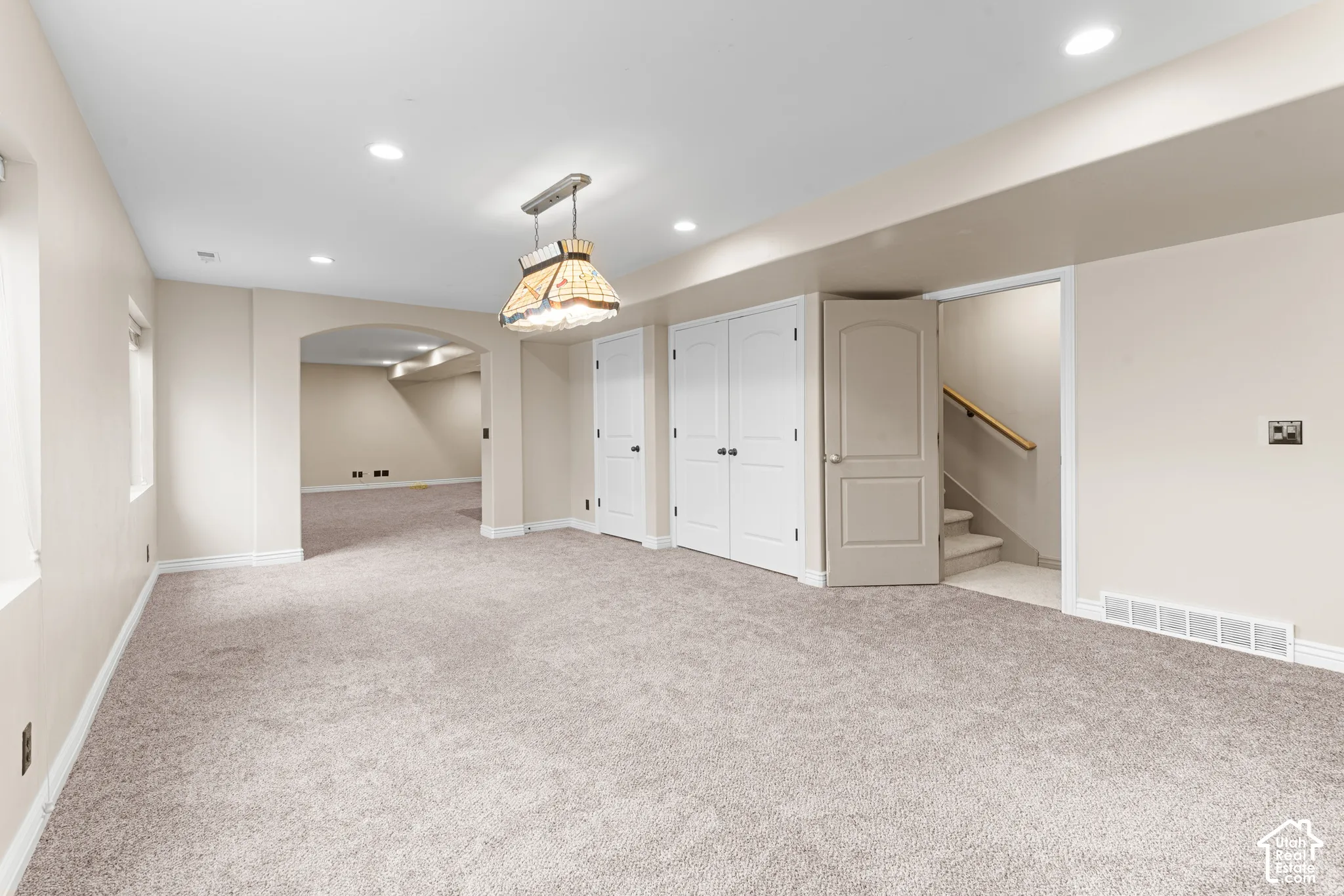 Recessed lighting, arched doorway, neutral carpeting, built-in storage closets, and interior stairway access