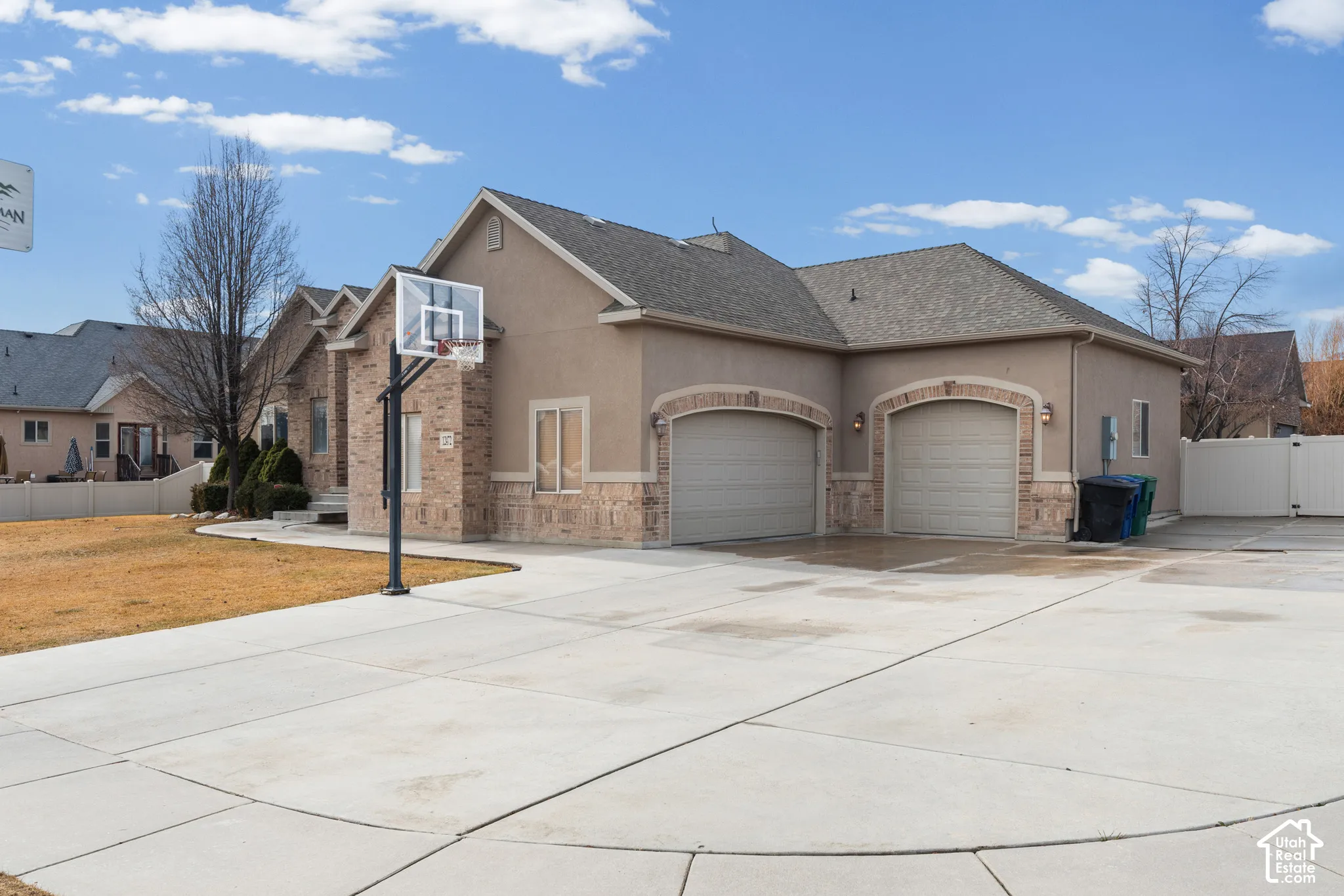 Stucco and brick exterior with a multi-car garage, arched garage door openings, and a concrete driveway