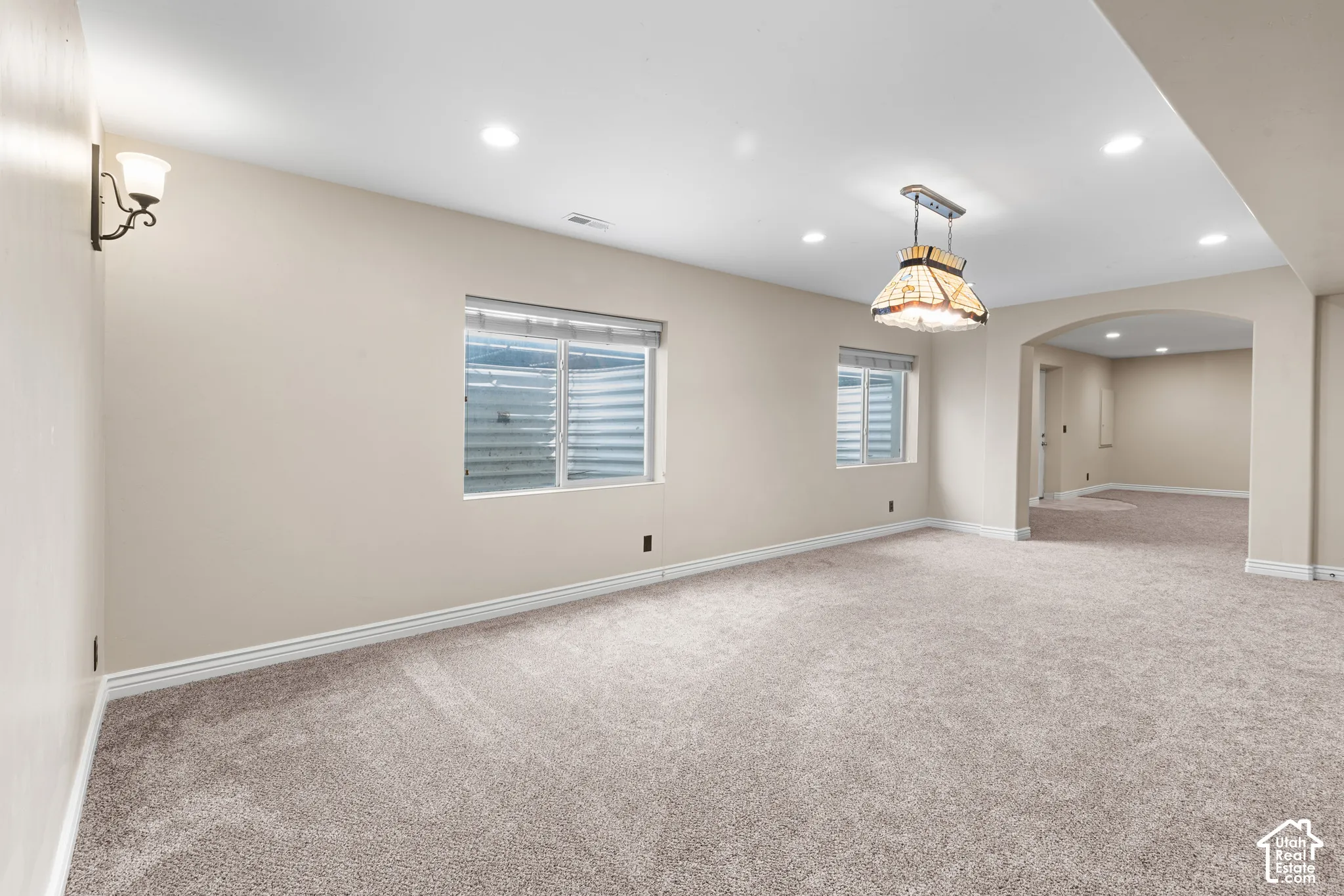Carpeted room with recessed lighting and two egress windows
