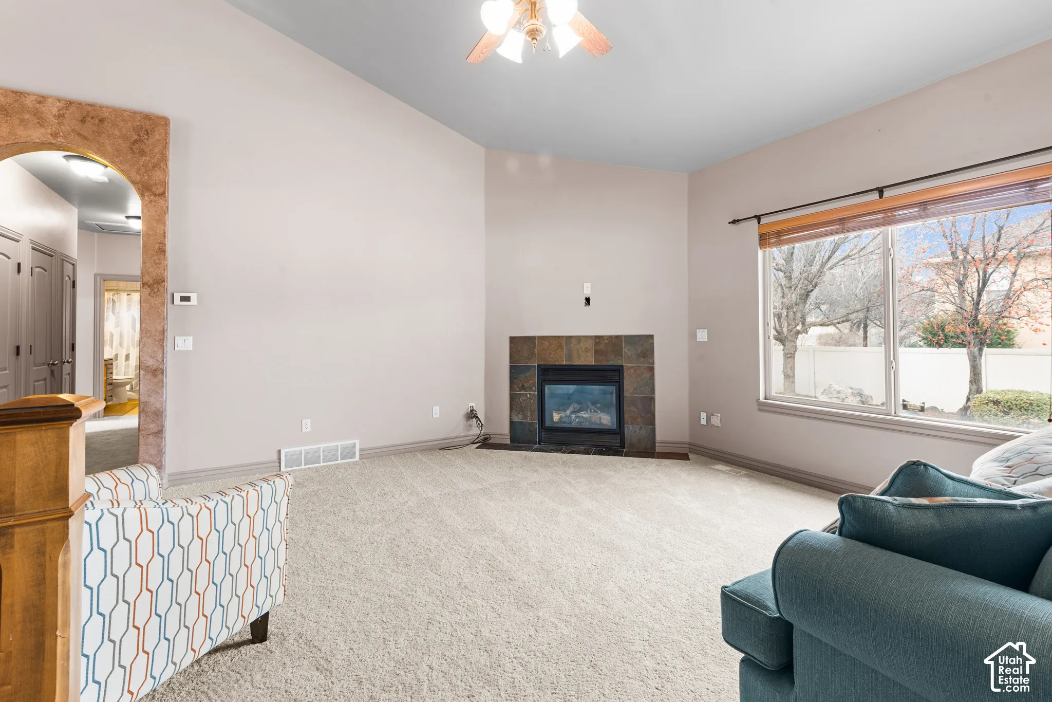 Spacious living area featuring a vaulted ceiling, a gas fireplace with a slate surround, and a large picture window