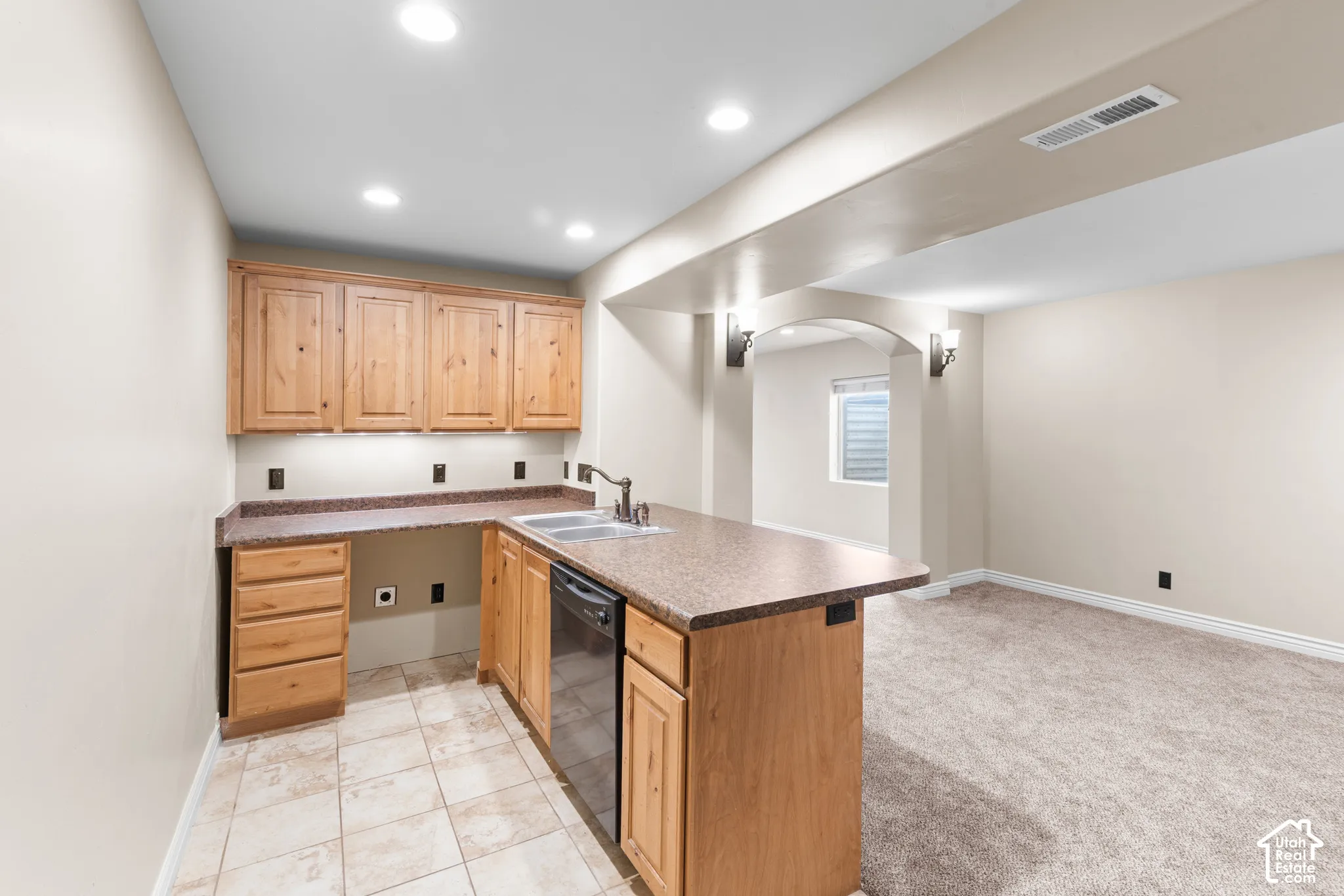 Kitchenette featuring wood cabinetry, speckled countertops, a stainless steel sink, and a built-in dishwasher