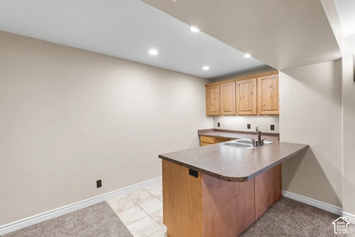 Built-in wet bar featuring wood cabinetry, a double basin sink, and a laminate countertop