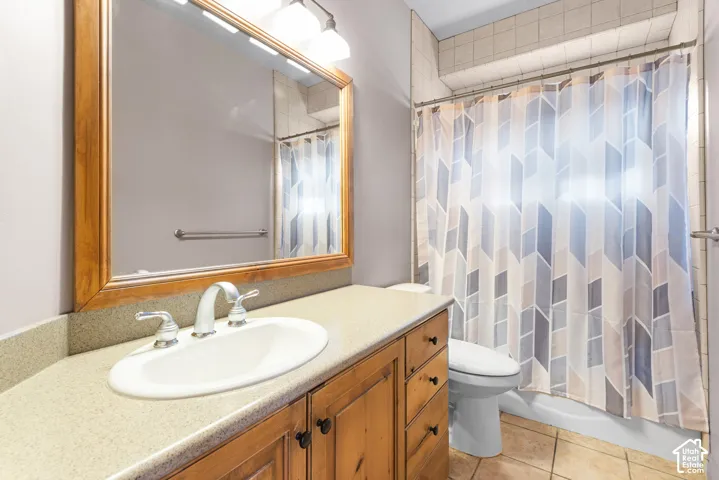 Bathroom featuring a wood-finish vanity with an integrated sink and brushed nickel faucet, a framed mirror with overhead lighting, and a tiled shower surround
