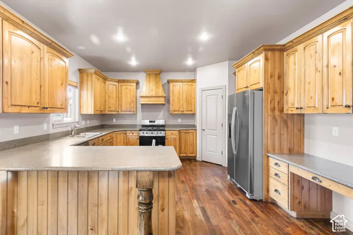 Spacious kitchen featuring extensive wood cabinetry, stone-finish countertops, stainless steel appliances, and wood-finish flooring