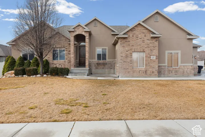 Stucco and brick exterior with a prominent arched entry, concrete porch, and mature foundation plantings