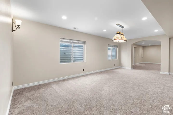 Carpeted room with recessed lighting and two egress windows