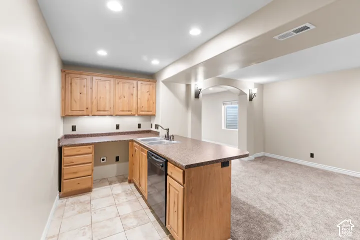Kitchenette featuring wood cabinetry, speckled countertops, a stainless steel sink, and a built-in dishwasher