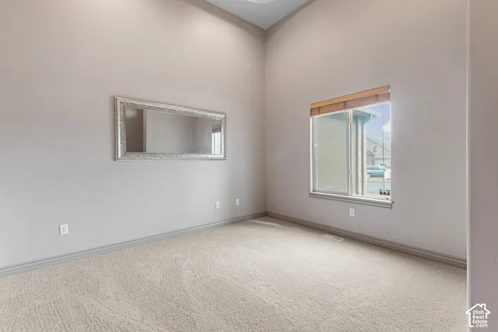 Vaulted ceiling, neutral wall paint, carpeted flooring, and window with wood-finish blinds