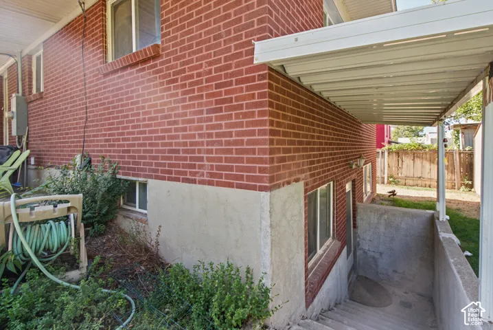 Brick exterior with a covered entry, concrete walkway, and basement access