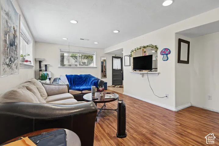 Recessed lighting illuminates the open living area featuring wood-finish flooring, white baseboards, and multiple windows