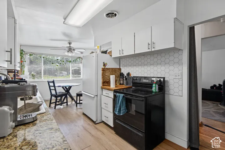White upper and lower cabinetry, a hexagonal tile backsplash, wood-finish flooring, and a ceiling fan