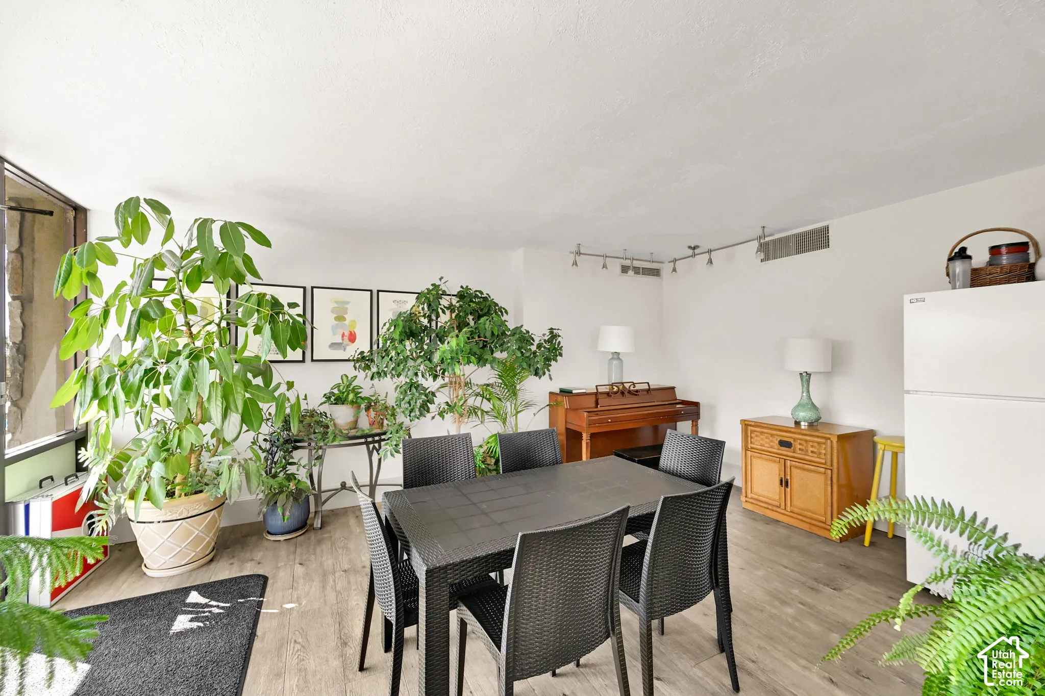 Spacious interior with wood-finish flooring, white walls, and track lighting