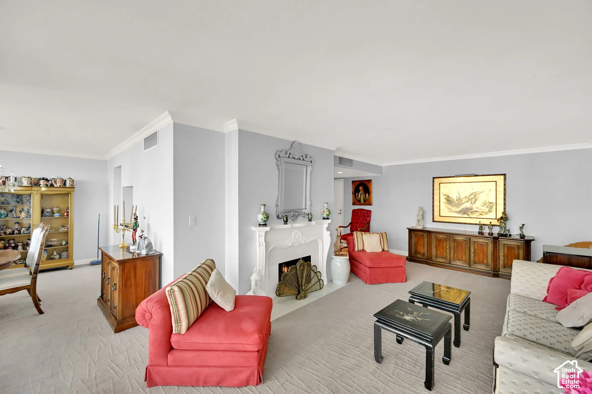 Open-concept living space featuring crown molding, a built-in fireplace with an ornate mantel, and carpeted flooring