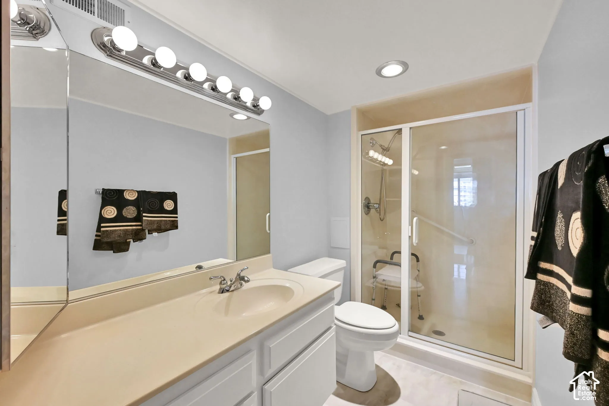 Bathroom featuring a single vanity with an integrated sink, framed mirror, and built-in lighting