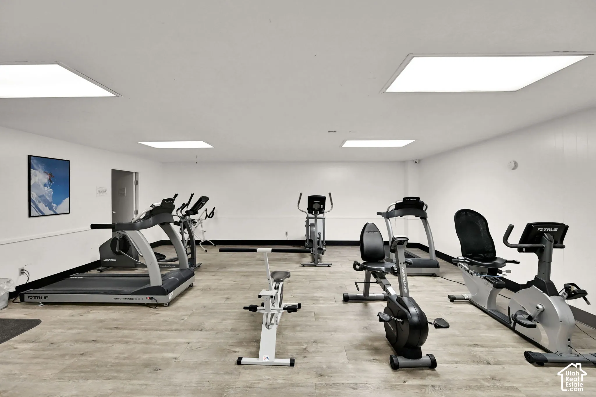 Fitness center with wood-finish flooring, recessed lighting, and white walls