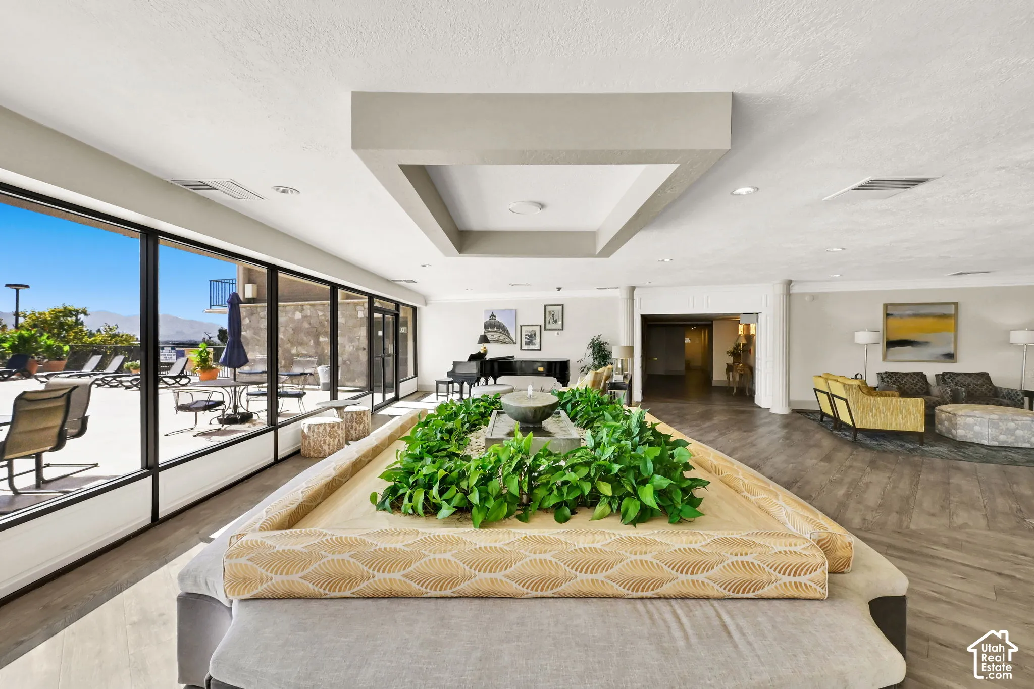 Open-concept living area featuring soaring ceilings with geometric architectural detailing, wide-plank wood-finish flooring throughout, and expansive sliding glass doors opening to outdoor space