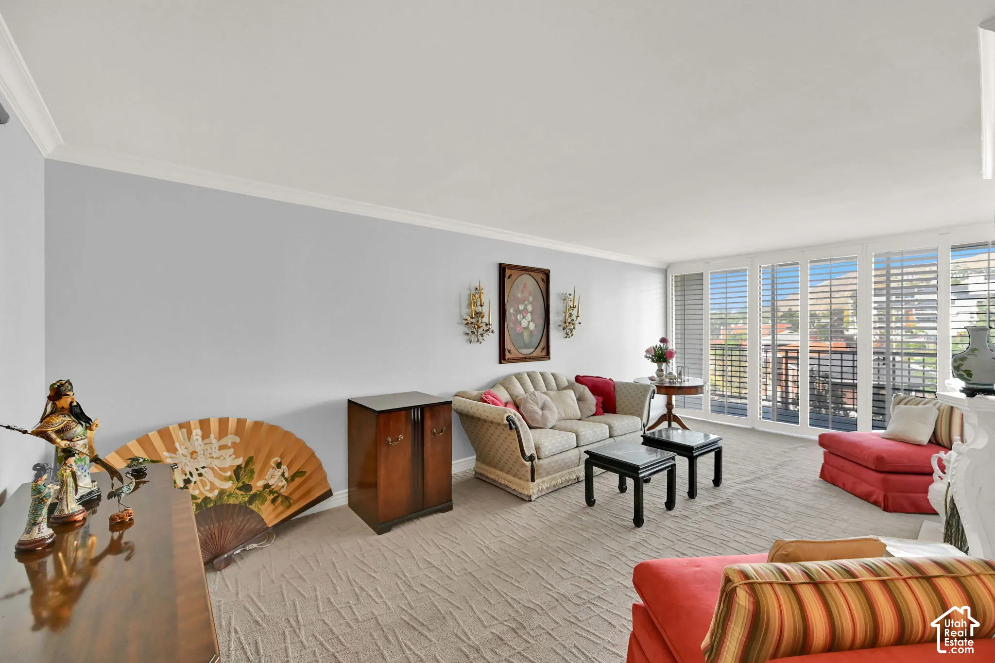 Spacious living area featuring crown molding, neutral wall color, and wall sconces