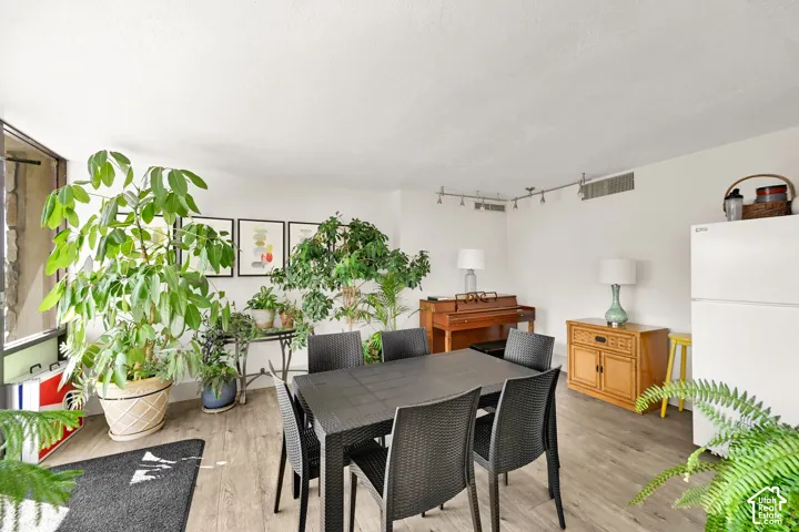 Spacious interior with wood-finish flooring, white walls, and track lighting
