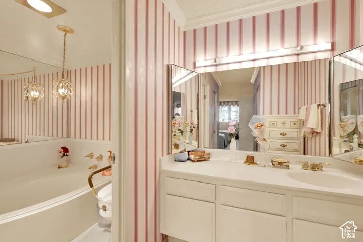 Built-in soaking tub, vanity with dual sinks, three-panel mirror, and wallpapered walls