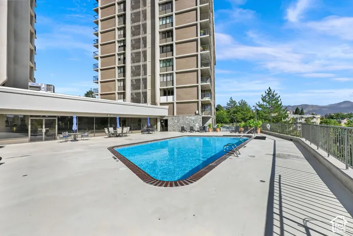 Outdoor swimming pool with a concrete deck, surrounded by a metal railing