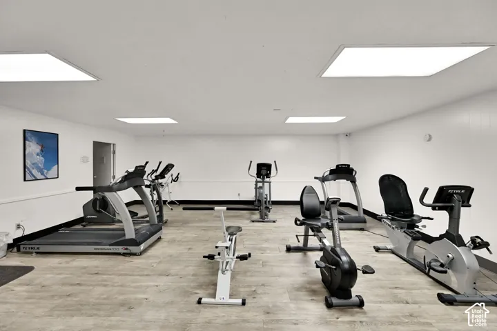Fitness center with wood-finish flooring, recessed lighting, and white walls