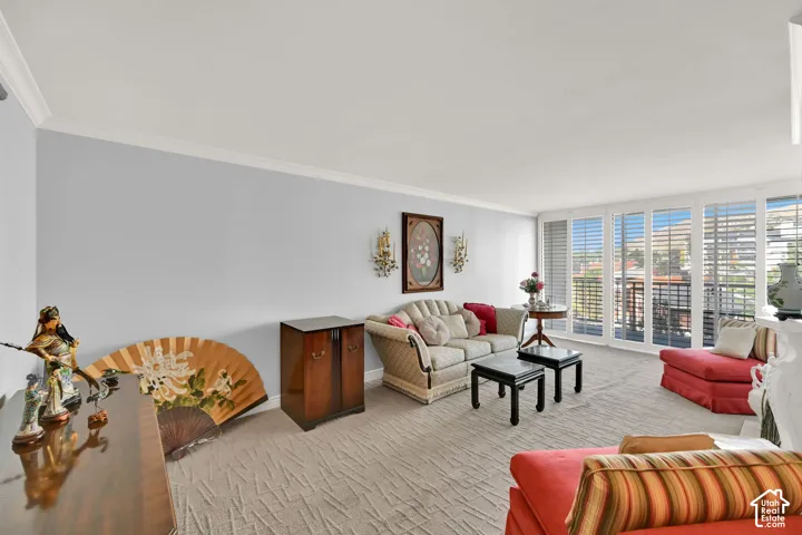 Spacious living area featuring crown molding, neutral wall color, and wall sconces