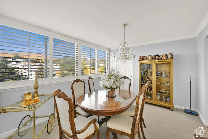 Wall-to-wall windows with plantation shutters, crown molding, and a crystal chandelier