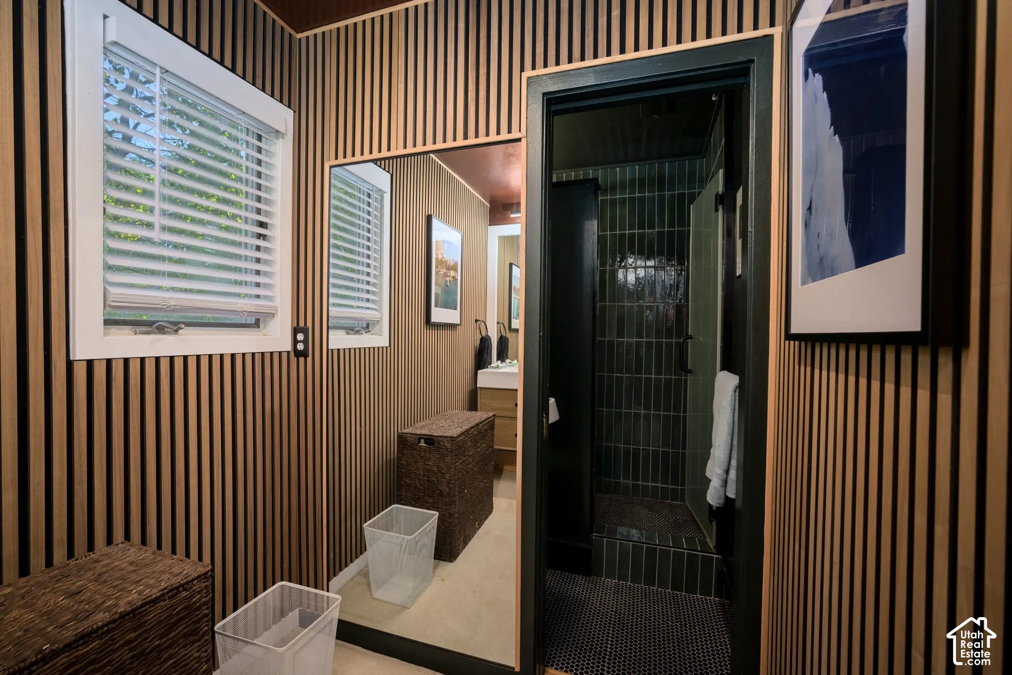 Wood slat wall paneling, white framed windows, full-height mirror, dark green tiled shower, black framed doorway