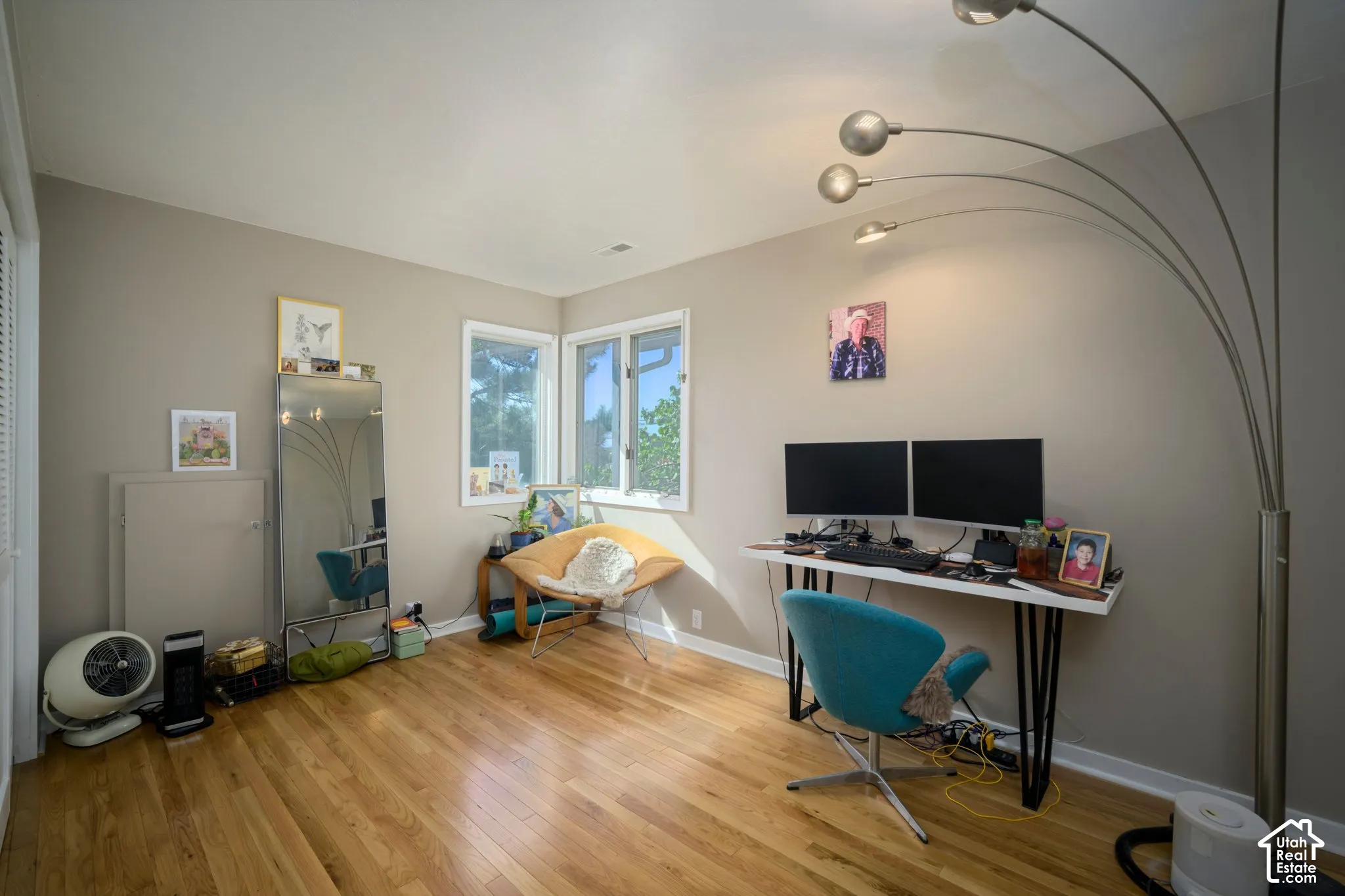 Hardwood flooring, corner window placement, neutral wall color, white trim, and a white ceiling