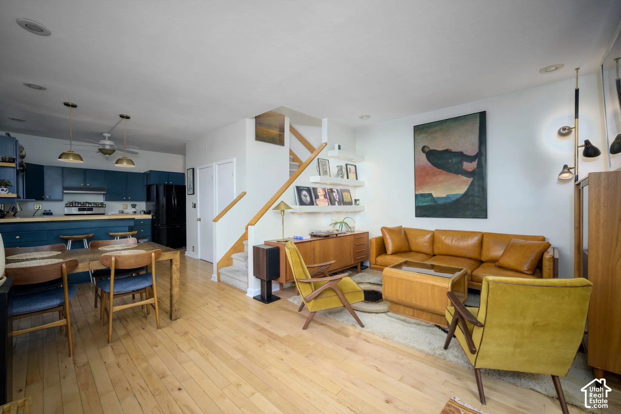 Open-concept living area with light wood-finish flooring, a staircase with wood railings, and built-in shelving