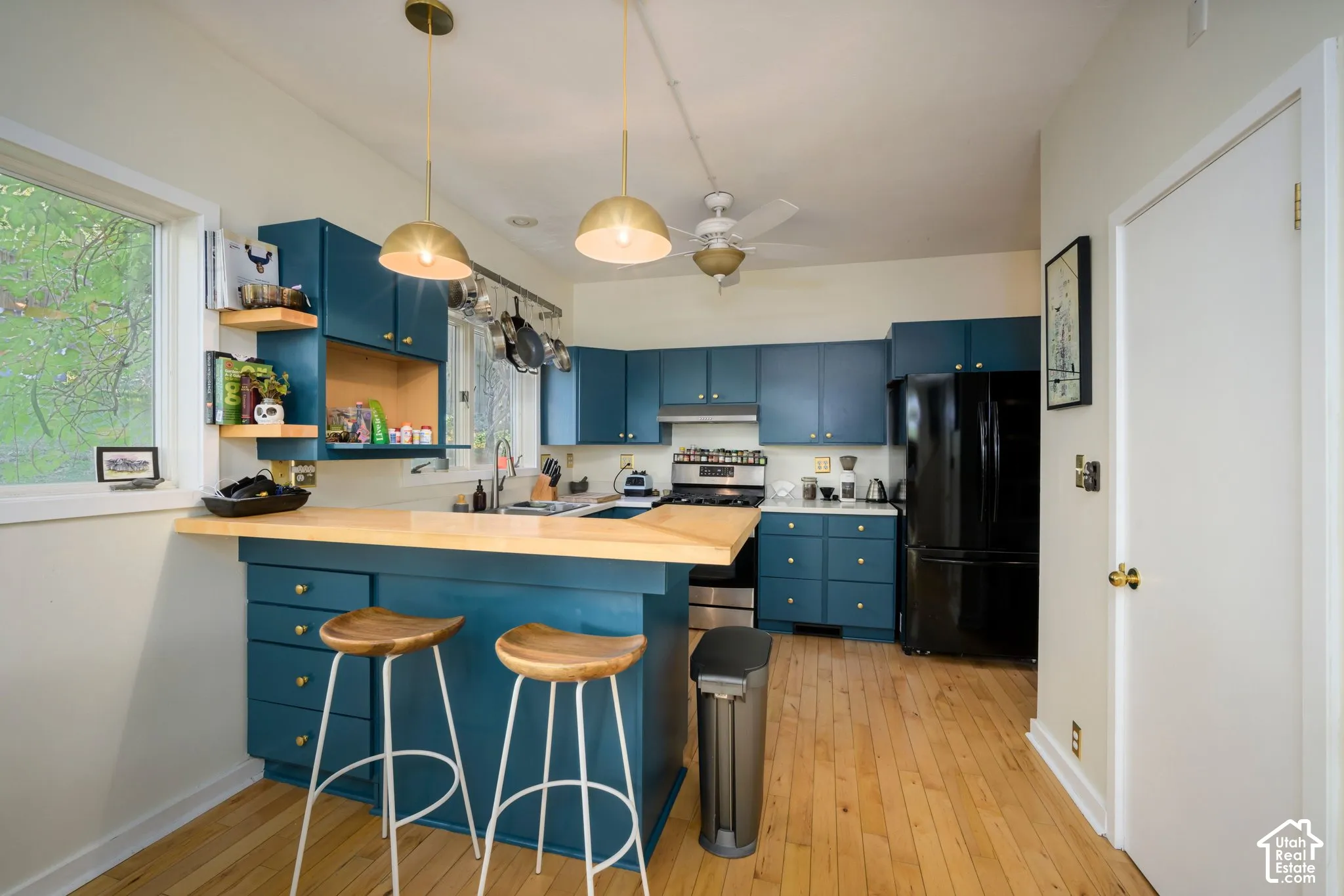 Kitchen featuring custom teal cabinetry, light wood-finish countertops, stainless steel range, and wood-finish flooring