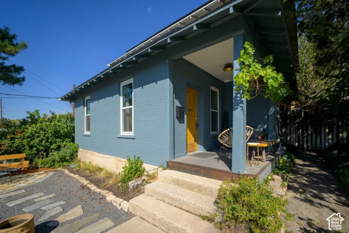 Blue brick exterior with white trim windows and a yellow entry door