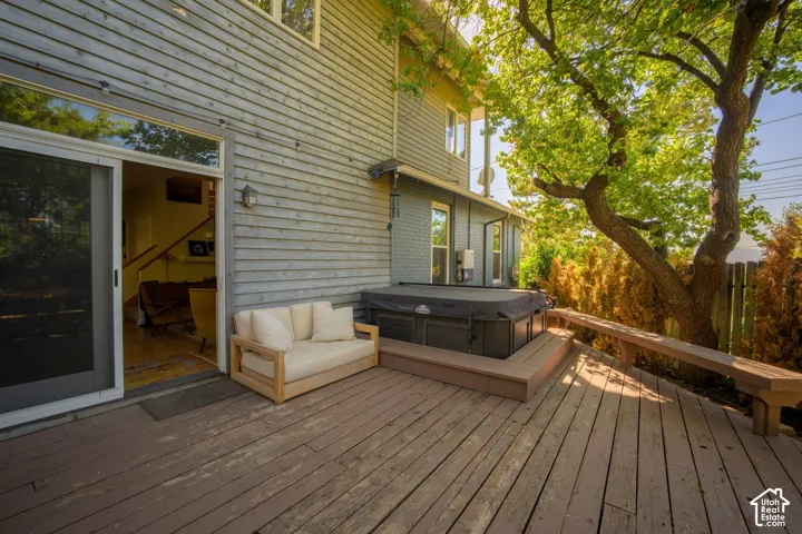Expansive wood deck with a built-in bench, integrated hot tub, and direct access through sliding glass doors