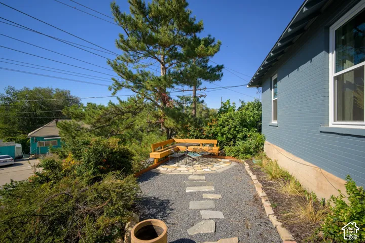 Exterior brick facade with white trim windows and a stone patio featuring a built-in wooden bench