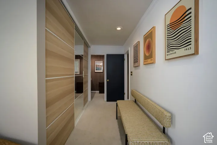 Hallway featuring wood-finish sliding closet doors, mirrored closet panels, recessed lighting, and light-toned carpeting