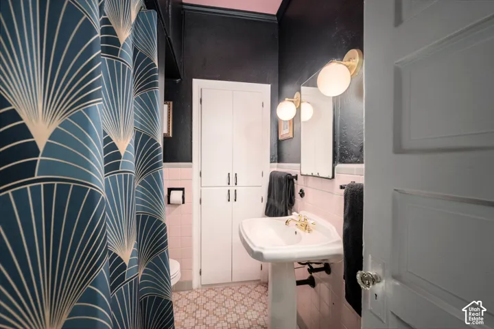 Pedestal sink with brass-finish faucet, wall-mounted spherical light fixtures, and white built-in cabinetry