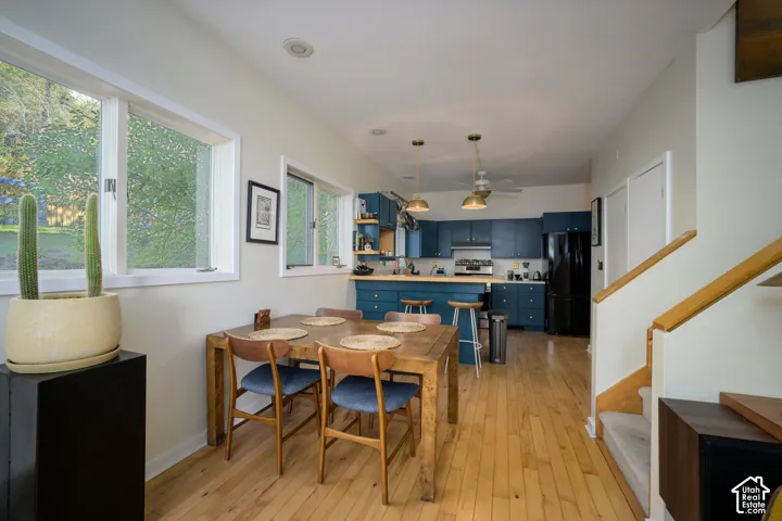 Open-concept living area with wood-finish flooring, multiple windows, and a staircase with natural wood railings