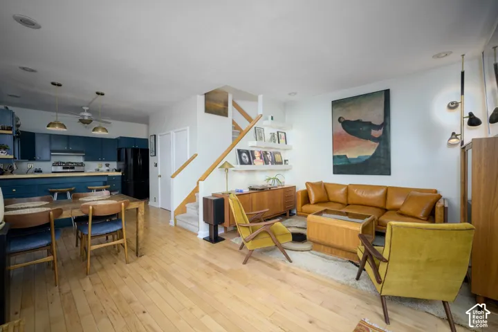 Open-concept living area with light wood-finish flooring, a staircase with wood railings, and built-in shelving