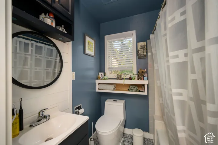 Vanity with integrated sink, black upper cabinet, round mirror, window with blinds, and built-in shelving